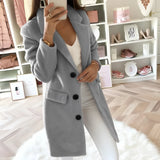 
A woman modeling a long black double-breasted blazer, tailored for an office chic look. The blazer features a structured collar, long sleeves, and is shown in a gray color, size 4XL. The model's hand is placed on her waist, highlighting the fashion-forward design and fit of the blazer.