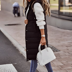 Women's long black puffer vest worn by a model standing, showcasing its urban chic winter style with knee-length, sleeveless design.