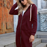 Women's long blue oversized zip-up hoodie with urban streetwear style, featuring relaxed shoulder seams and long sleeves, worn by a model with sunglasses.