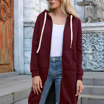 
A woman wearing a long blue oversized zip-up hoodie styled in urban streetwear fashion, with a focus on the shoulder and sleeve details. She is also wearing sunglasses and jeans, creating a casual and trendy look.