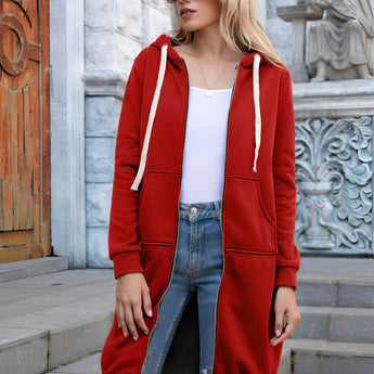 A woman wearing a long blue oversized zip-up hoodie styled as urban streetwear, paired with sunglasses, showcasing a casual and trendy fashion look.