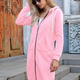 
A woman wearing a long blue oversized zip-up hoodie, embodying urban streetwear style. She is accessorized with sunglasses and standing against a white background.