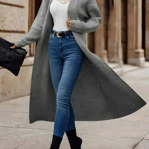 Women's long grey coat with a stylish urban chic design, featuring a tailored fit with defined shoulders, a high neck, full sleeves, and a waist-cinching silhouette.