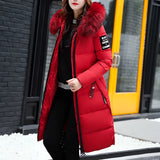 
A red women's long puffer jacket with a fur-trimmed hood, designed as an insulated winter coat. The jacket features a fitted waist, full-length sleeves, and a stylish, warm collar, available in size 3XL.