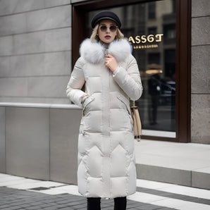 Women's long winter coat with a fur hood, featuring a quilted design, shown on a model. The coat is insulated for warmth and has a waist-cinching silhouette. The model is wearing sunglasses and a hat.
