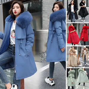
A woman wearing a long winter parka with a blue fur collar, featuring an adjustable waist. The parka is styled with long sleeves and appears to be made from a durable textile material, suitable for cold weather. The image captures the parka from a front angle, highlighting its outerwear design and functionality.
