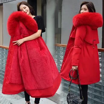 
A woman wearing a red long winter parka in size 6XL, featuring a distinctive blue fur collar, adjustable waist, and long sleeves. The parka has a tailored fit, showcasing a stylish and warm design suitable for cold weather. The woman is standing, highlighting the coat's full length and functional fashion appeal.