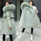 Women's long winter parka in green, featuring a blue fur collar, adjustable waist, and long sleeves. The parka is designed for warmth and style, suitable for cold weather.