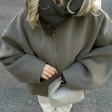 Oversized green high-collar hoodie worn by a woman, styled with sunglasses, showcasing urban fashion.
