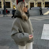 
A woman wearing an oversized green high-collar hoodie, styled for urban fashion, standing on a sidewalk. The hoodie is in a light green color and size large, featuring long sleeves and a relaxed fit, ideal for a casual and stylish outdoor look.