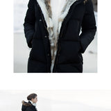 Women's luxury white puffer jacket with a fur hood, featuring long sleeves and a sleek design, worn by a person standing and posing, showcasing the winter coat's elegant and stylish appearance.