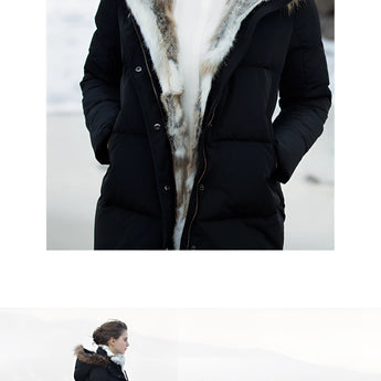 Women's luxury white puffer jacket with a fur hood, featuring long sleeves and a sleek design, worn by a person standing and posing, showcasing the winter coat's elegant and stylish appearance.