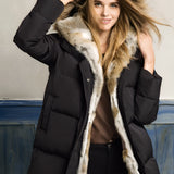 
A woman wearing a luxurious white puffer jacket with a fur hood, showcasing a stylish winter coat. The jacket is complemented by her smiling face and natural hair.