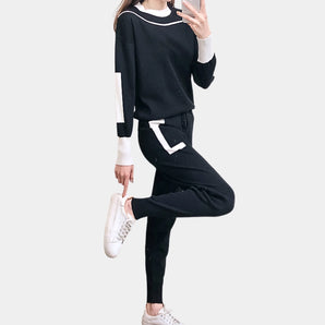 
A woman wearing a black and white athletic set consisting of a long-sleeve sweatshirt and jogger pants.