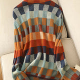 Women's oversized fall sweater in a multicolor plaid pattern with orange accents, featuring long sleeves and cozy knit fabric.