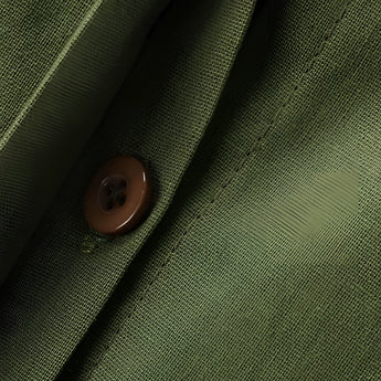 Women's navy blue linen shirt and pants set displayed against a light, neutral background featuring wooden textures and beige accents. The outfit is designed for a casual summer look, highlighting a structured collar and a comfortable, relaxed fit.