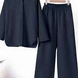 Women's navy blue linen shirt and pants set hanging on a clothes hanger, featuring a collared shirt with long sleeves, designed as a casual summer outfit.
