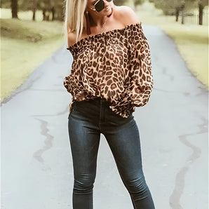 Women's off-shoulder leopard print blouse with long sleeves, styled with blue jeans and sunglasses.