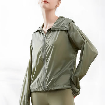 Woman wearing an olive green hooded windbreaker, lightweight and breathable with a zip-up front, in a size large.