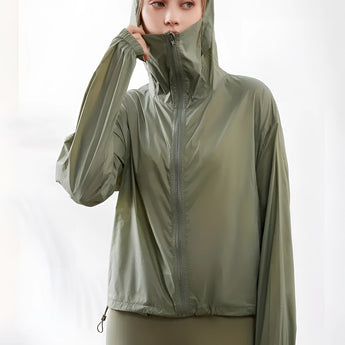 A woman wearing an olive green hooded windbreaker with a zip-up front, showcasing long sleeves and a lightweight, breathable design.