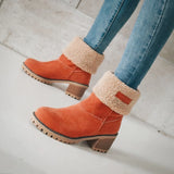 Women's orange suede ankle boots featuring a sherpa lining and chunky heel, shown on a person’s feet.