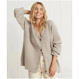 
Woman wearing a light gray oversized chunky knit wool cardigan, styled casually with a relaxed fit, featuring long sleeves and a cozy collar, suitable for winter wear.