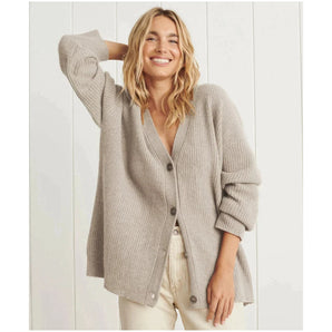 
Woman wearing a light gray oversized chunky knit wool cardigan, styled casually with a relaxed fit, featuring long sleeves and a cozy collar, suitable for winter wear.