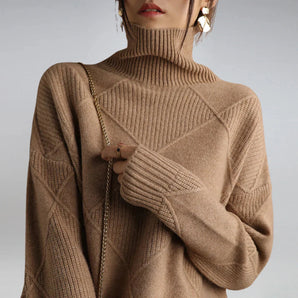 Women's oversized beige turtleneck chunky cable knit sweater with long sleeves, featuring a textured design and a relaxed fit.