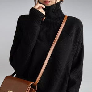 
Image of a women's oversized black cashmere turtleneck knit sweater featuring long sleeves and a relaxed fit. The sweater covers the shoulders and neck, providing a cozy and elegant look.