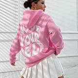 
A woman wearing an oversized pink pullover hoodie. The hoodie is styled as a piece of loungewear, featuring a comfortable and relaxed fit with long sleeves and a roomy neckline.