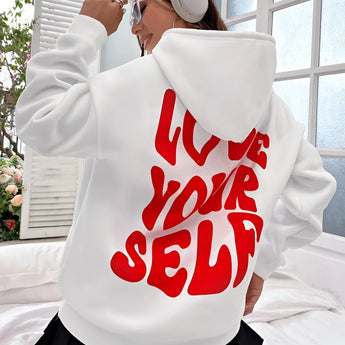
A woman wearing an oversized black pullover hoodie with long sleeves, looking happy. The hoodie is part of stylish and comfy lounge wear, suitable for casual and relaxed environments.