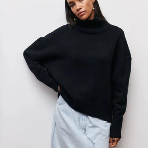 
A woman wearing an oversized black turtleneck sweater showcasing its long sleeves and high collar, ideal for casual winter wear.