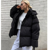 
Image of a woman wearing a trendy oversized blue hooded puffer jacket, featuring long sleeves and a high collar, styled for winter fashion.