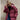
A woman wearing a wine red oversized hooded puffer jacket with a trendy winter fashion design. She is smiling and appears happy, with the jacket featuring long sleeves and a waist length.