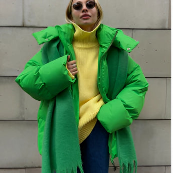 
A woman wearing an oversized green hooded puffer jacket in a large size, showcasing trendy winter fashion with visible sleeves and a collar.