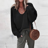
A woman wearing an oversized gray V-neck sweater showcasing a relaxed fit, suitable for autumn. The sweater features long sleeves and a comfortable drape over the shoulder and waist. The model is posing, highlighting the sweater's casual style.