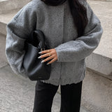 Women's oversized gray wool blend coat featuring a chunky knit design, with a large collar and long sleeves. The coat falls to the knee, providing a warm and stylish option for winter fashion in a muted gray color.
