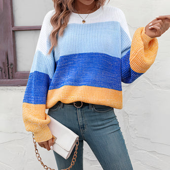 
A cozy women's oversized knit sweater with pastel aqua and purple stripes, worn by a person paired with jeans. The sweater features a relaxed fit, extending over the shoulders and arms, creating a casual and comfortable look.