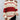 
A woman wearing an oversized red stripe off-shoulder sweater, styled for autumn fashion, showcasing the arm and shoulder areas with white and red stripes. The sweater features a jersey-knit texture with long sleeves and a loose fit, suitable for casual wear. The variant style is XL.
