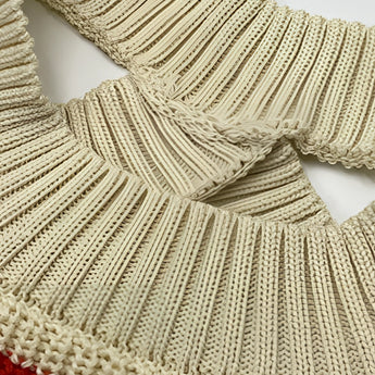 Women's oversized red and beige striped off-shoulder sweater displayed on a wooden hanger against a neutral background, showcasing the woolen texture and casual autumn fashion style.