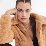 A woman wearing an oversized plush red teddy coat, suitable for winter, with the coat's soft texture and warm fabric prominently displayed.