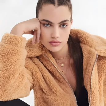 A woman wearing an oversized plush red teddy coat, suitable for winter, with the coat's soft texture and warm fabric prominently displayed.