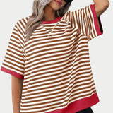 
A woman wearing an oversized red and pink striped tee with a loose fit, featuring long sleeves and a round neckline.