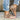 Brown peep-toe wraparound ankle sandals in an earth tone bohemian style, worn by a person pairing them with denim jeans, showcasing the shoe's flat sole and stylish design.