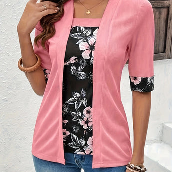 Woman wearing a pink cardigan over a floral blouse, paired with jeans, smiling and posing casually.