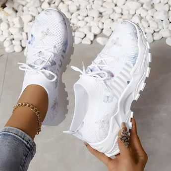 Women's pink floral mesh running shoes in white, featuring lightweight and breathable design, shown on a person's foot.