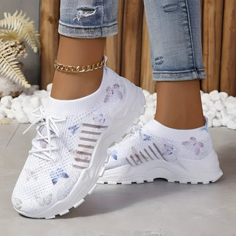 Women's pink floral mesh running shoes featuring a lightweight and breathable design, shown on a model wearing denim jeans.