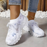 Women's pink floral mesh running shoes with white soles, worn by a person dressed in grey denim sportswear.