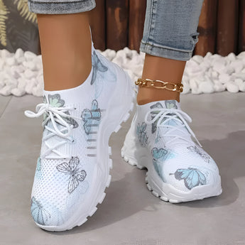 Women's pink floral mesh running shoes being worn, showcasing their lightweight and breathable design, with a focus on the fashionable floral pattern against a white and aqua background.