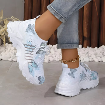 Women's pink floral mesh running shoes, lightweight and breathable sneakers with a vibrant floral pattern, displayed on a model wearing jeans.